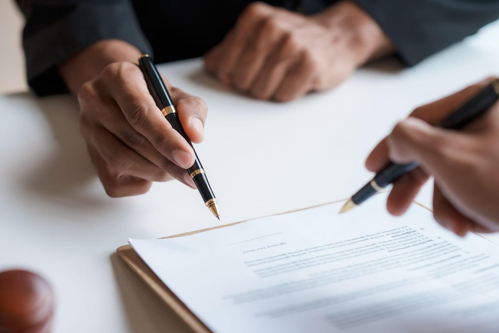A business agreement being signed with pens on white paper